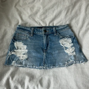 Blå jeanskjol från Hollister - Snygg blå jeanskjol från Hollister med slitna detaljer och fransig nederkant. Midjemått ca 33 cm rakt över, längd ca 24 cm 💗