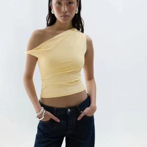 Gul asymmetrisk topp - Gul asymmetrisk topp från Gina Tricot i storlek xs men passar även en S. aldrig använd, endast testad och därav säljer jag den🌸