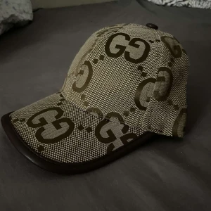 Beige keps från Gucci med GG-mönster - Snygg beige keps från Gucci med ikoniskt GG-mönster i brunt. Kepsen har böjd skärm med mörkbrun kant och är tillverkad i ett slitstarkt tyg. Pris kan diskuteras 
