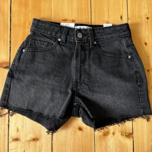 Svarta jeansshorts från STAY XS - Svarta jeansshorts från STAY i modellen Mid Shorts. Klassisk femficksdesign, råa fransiga benslut och midja med knapp och dragkedja. Snyggt avslappnad look, perfekt till sommaren. Materialet är denim och shortsen har bälteshällor.