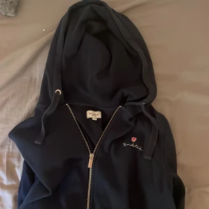 Zip hoodie bondelied - Snygg mörkblå hoodie från Bondelid med hel dragkedja och huva med snörning. Broderad logga på bröstet och klassisk passform. Perfekt för chill dagar eller när du vill ha en enkel och stilren look. Det är storlek M men sitter som S