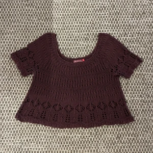 Stickad brun topp från INDISKA - Gullig stickad topp från märket INDISKA i lite rosa mörkbrun färg. Modellen är croppad med korta ärmar och har ett snyggt virkat mönster med håldetaljer. Perfekt för lager-på-lager och faller fint på axlarna i en mer off shoulder look med trekvartslånga ärmar. Ganska djup i ryggen. Skicket är ganska bra men den är lite nopprig. Skriv gärna om ni har några frågor!!