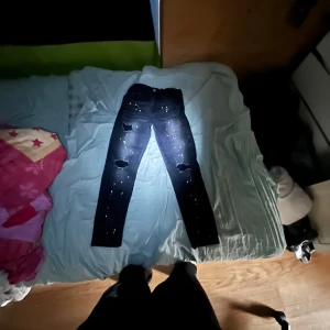 Svarta jeans me färg prickar och tre hål - Jag säljer ett par svarta Jeans med gula och vita färg prickar på för dom är för små och vill få dom sålda det är storlek 158-162 cm knappt använda har använt dom typ 3 gånger jag gillade dem inte jätte mycket. Jag vet inte vilket märke det är på byxorna min mamma köpte dom till mig.