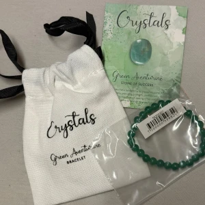 Grönt aventurinarmband Crystals - Stilrent armband med runda pärlor av grön aventurin från Crystals. Kommer i en vit tygpåse med svart snörning och medföljande kort om stenen. Perfekt accessoar för dig som gillar kristaller och vill addera lite färg till din look. Stone of Success ☘️