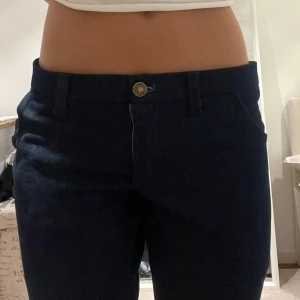 Mörkblå bootcut jeansbyxor - Snygga mörkblå jeansbyxor med bootcut passform och hög midja. Klassisk design med fickor både fram och bak samt hällor för bälte.