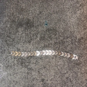 Silverfärgat armband från Lacoste - Stilrent armband i silverfärgad metall från Lacoste med klassisk krokodil-logga på spännet. Länkarna har en cool, geometrisk design med mönstrad yta som ger extra edge till din look. Perfekt accessoar för dig som gillar sportig och clean stil.