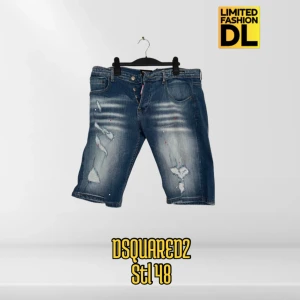 Dsquared2 jeansshorts blå stl 48 - Snygga blå jeansshorts från Dsquared2 med slitna detaljer och coola slitningar framtill. Klassisk femficksmodell med knappgylf och medelblå tvätt. Perfekta för dig som vill ha en avslappnad och trendig look i sommar.