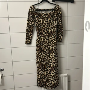 Leopardmönstrad långklänning - Snygg långklänning med leopardmönster och figurnära passform. Klänningen har långa ärmar och rundad halsringning. Perfekt för dig som vill sticka ut med ett djurmönstrat plagg. Materialet känns mjukt och följsamt.
