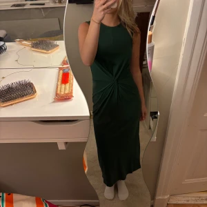 Mörkgrön långklänning från Mango - Supersnygg mörkgrön långklänning från Mango i mjuk bomull. Ärmlös modell med rund halsringning och cool twistad detalj i midjan som ger en smickrande siluett. Perfekt för dig som gillar stilrena och trendiga plagg.