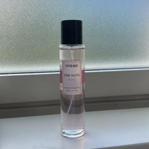 R&R de Mayo One Note Rose parfym - Fräsch Eau de Toilette med rosdoft från R&R de Mayo. Flaskan är cylinderformad i genomskinligt glas med svart plastkork och rosa detaljer på etiketten. Innehåller 100 ml. Perfekt för dig som gillar blommiga och lätta dofter.