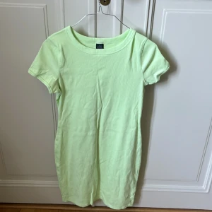 Ljusgrön t-shirtklänning Wild Fable - Enkel och fräsch ljusgrön t-shirtklänning från Wild Fable. Modellen är kort med rund halsringning och korta ärmar. Tillverkad i mjuk, ribbad bomull som sitter skönt och har en slim passform. Perfekt för en chill och avslappnad look.