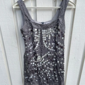 Silver paljettopp från Chanel - Supersnygg silverfärgad topp från Chanel med breda axelband och massor av stora paljetter framtill. Toppens material har en glansig finish och cool struktur, perfekt för att sticka ut. Dragkedja i ryggen för enkel påklädning. En riktig statement-piece för dig som gillar att glänsa.