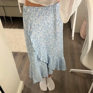 Blommig blå omlottkjol  - Super söt kjol som är i mycket bra skick! Super bekväm att ha på sig och perfekt nu i sommar :) 