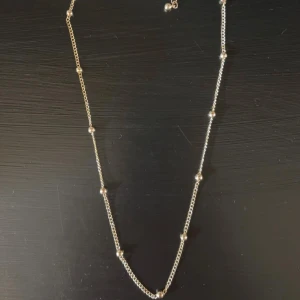 Tunt guldhalsband med små kulor - Snyggt och minimalistiskt halsband i guld med små runda kulor jämnt fördelade längs kedjan. Perfekt för att ge en stilren touch till din outfit. Kedjan är tunn och smidig, vilket gör den enkel att bära varje dag. Mycket bra skick