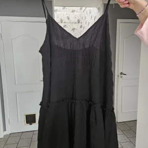 Svart sommarklänning med smala axelband - En svart, luftig kortklänning med smala axelband och v-ringning. 