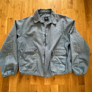 Blå jeansjacka från Zara - Snygg blå jeansjacka från Zara med dragkedja framtill, stora fickor med lock och tryckknappar ny pris 699