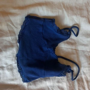 Marinblå  sommartopp - Supersöt marinblå linnetopp med tunna axelband och fina spetsdetaljer längs kanterna. Toppen är ribbad och har en mjuk, stretchig känsla som gör den riktigt bekväm. Perfekt att styla med jeans eller kjol för en chill look. från pull and bear