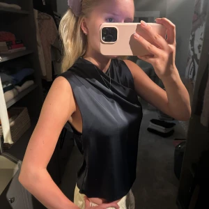 Mörkblå satin topp med drapering - Snygg mörkblå ärmlös topp i satin med draperad halsringning. Toppen har en lätt glansig finish och en lös passform som ger en cool och elegant vibe. Aldrig använd 🌟