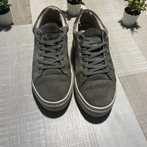 Grå mockasneakers från Vagabond - Snygga grå sneakers från Vagabond i mocka med klassisk rund tå och platt vit sula. Skorna har snörning med metallöljetter och en stilren, minimalistisk look som passar till det mesta. Perfekta för dig som gillar enkel och clean stil. Skulle säga att dom passar en storlek större!