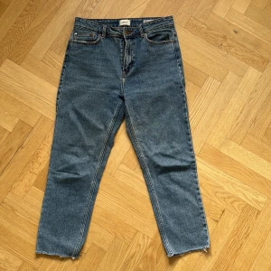 ONLY Emily high waisted jeans - Snygga blå jeans från ONLY, modell Emily med hög midja och raka ben. Klassisk femficksdesign, råa kanter nertill och cool vintagekänsla. Perfekta till sneakers eller boots. Tillverkade i slitstarkt denim.