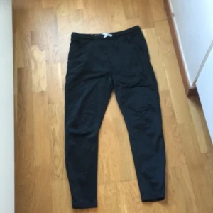 Svarta gympabyxor med dragkedja - Säljer ett par svarta gympabyxor med snörning i midjan och dragkedjor vid bensluten. Perfekta för en avslappnad stil och för skogen.