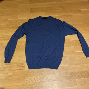 Blå tröja från Lawrence Grey - Säljer en stilren blå tröja från Lawrence Grey. Tröjan har en klassisk rund hals och långa ärmar med ribbade muddar. Perfekt för en avslappnad och snygg look.