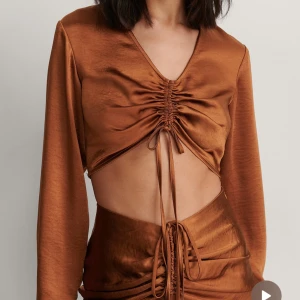 Brun satinblus med knytning - Snygg brun satinblus med v-ringning och knytning framtill från nakd 