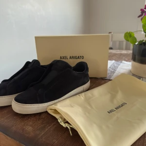  Axel Arigato  - Snygga marinblå skor i modell clean 360 laceless. Skorna har en vit sula och är perfekta för en avslappnad stil. Allt og till kommer.