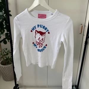 Vit ribbad tröja från Maison Rapito - Säljer en vit ribbad tröja från Heart Club med ett kattmotiv och texten 'My Pussy My Choice' i blått och rött. Tröjan har långa ärmar och en rund halsringning. Perfekt för en statement-look!