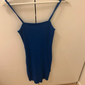Blå ärmlös klänning - Snygg blå ärmlös klänning med smala axelband. Perfekt för sommarens varma dagar. Klänningen har en enkel och stilren design som passar till många tillfällen.