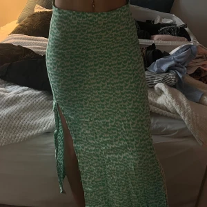 Grön mönstrad långkjol - Snygg grön långkjol med ett subtilt mönster och en slits på sidan från H&M. Kommer passa en xxs/ mindre xs. Jag är 166 cm lång. Aldrig använt 