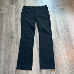 Svarta kostymbyxor bootcut - Snygga svarta kostymbyxor från Stockh LM i storlek 36. Byxorna har en klassisk design med utsvängda ben och knappstängning. Perfekta för en stilren look. 