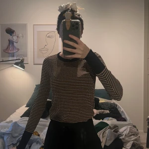 Mönstrad stickad tröja från Zara - Säljer en snygg stickad tröja från Zara med ett coolt prickigt mönster i svart, beige och rött. Tröjan har långa ärmar och en rund halsringning med svarta kanter. 