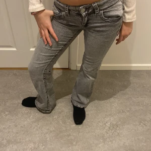 Grå lågmidjade jeans - Snygga grå jeans med låg midja och bootcut-stil. De har en klassisk femficksdesign och knappar fram. Perfekta för en avslappnad look.