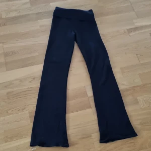 Svarta byxor från Gina Tricot - Snygga svarta byxor från Gina Tricot med ribbad midja. Byxorna har en bootcut-stil som ger en trendig look. Perfekta för en avslappnad stil.