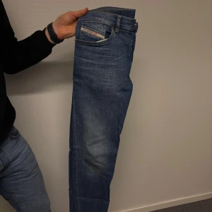 Blå jeans från Diesel - Snygga blå jeans från Diesel med klassisk femficksdesign och knappgylf. Jeansen har en modern passform och är tillverkade i en bomullsblandning för extra komfort. Perfekta för en avslappnad stil.