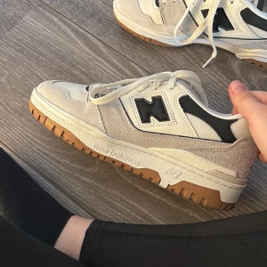 New Balance 550 sneakers - Snygga New Balance 550 sneakers i vit och svart med snörning. Skorna har en brun sula och är perfekta för en casual look. De är en stor 38! 
