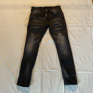Svarta jeans dsquared2 - Svarta jeans från dsquared2 med lite färgstänk och slitningar, jeansen är slim fit och sitter väldigt skönt längs med benen. INGET OG! PRISET KAN DISKUTERAS VID SNABB AFFÄR!