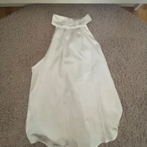 Vit ärmlös blus - Säljer en stilren vit ärmlös blus med hög krage. Perfekt för en elegant look. Glansigt material 💓