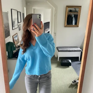 Blå tröja från Monki - Säljer en fin blå tröja från Monki med v-ringning och krage. Tröjan har långa ärmar och är tillverkad i ett mjukt material. Knappt använd