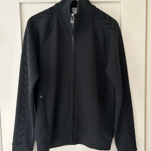 Svart jacka från Bottega Veneta - Snygg svart jacka från Bottega Veneta med dragkedja framtill. Jackan har ett diskret mönster längs ärmarna och en stilren design. Perfekt för en modern och stilren look.