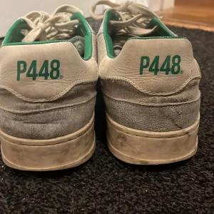 Grå sneakers från P448 - Snygga grå sneakers från P448 med gröna detaljer på insidan. Skorna har en klassisk snörning och är tillverkade i mocka. Perfekta för en stilren look. Egentligen väldigt oanvända men har lyckats smutsa ner dom, går att fixa men jag har inte orkat. Priset kan diskutera men 400kr är väldigt rimligt då jag köpte dom för mer än 2000kr 