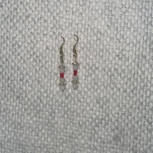 Örhängen med vita och röda pärlor - Snygga örhängen med vita och röda pärlor. De har en enkel design med små vita pärlor och en röd pärla i mitten. Perfekta för att ge en färgklick till din outfit.