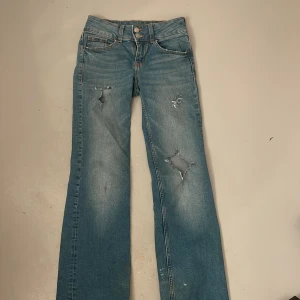 Blå jeans från H&M Divided lowwaist - Snygga blå jeans från H&M Divided med slitna detaljer och en klassisk femficksdesign. Lowwaist❤️