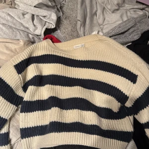 Randig stickad tröja från Name It - Säljer en mysig stickad tröja från Name It med breda ränder i beige och mörkblått. Tröjan har en croppad passform och långa ärmar, perfekt för en avslappnad stil. Passar åldrarna 11-12 år. passar bra på äldre ålder också 