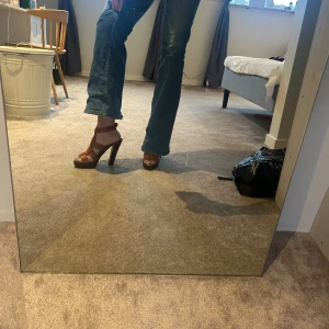 Bruna klackskor med remmar - Snygga bruna klackskor från Ralph Laurent Purple Collection, med remmar och öppen tå. Perfekta för att ge en elegant touch till din outfit. Klackarna är höga och ger en fin siluett. Har en lite sliten sula på ena skon. 