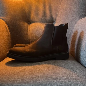 Svarta chelsea boots - Snygga svarta chelsea boots i mocka  med elastiska paneler på sidorna för enkel på- och avtagning. Perfekta för en stilren look. I storlek 45