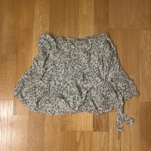 Blommig omlottkjol - Söt blommig omlottkjol i ljusa färger med knytband. Perfekt för en avslappnad och stilren look.