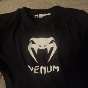 Svart t-shirt från Venum - Svart t-shirt från Venum med ett stort vitt tryck på framsidan. 