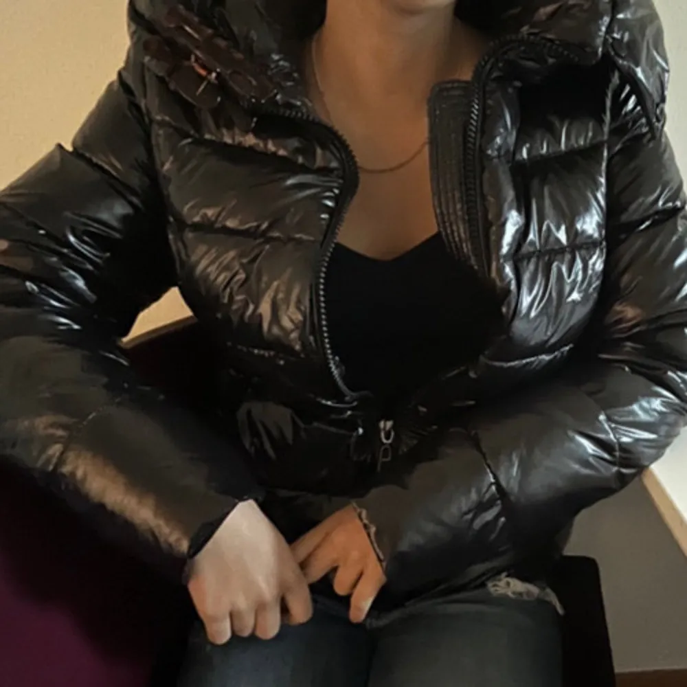 Snygg svart glansig dunjacka med dragkedja och huva. Andvänd många gånger men det syns inte att den är de. Takit.